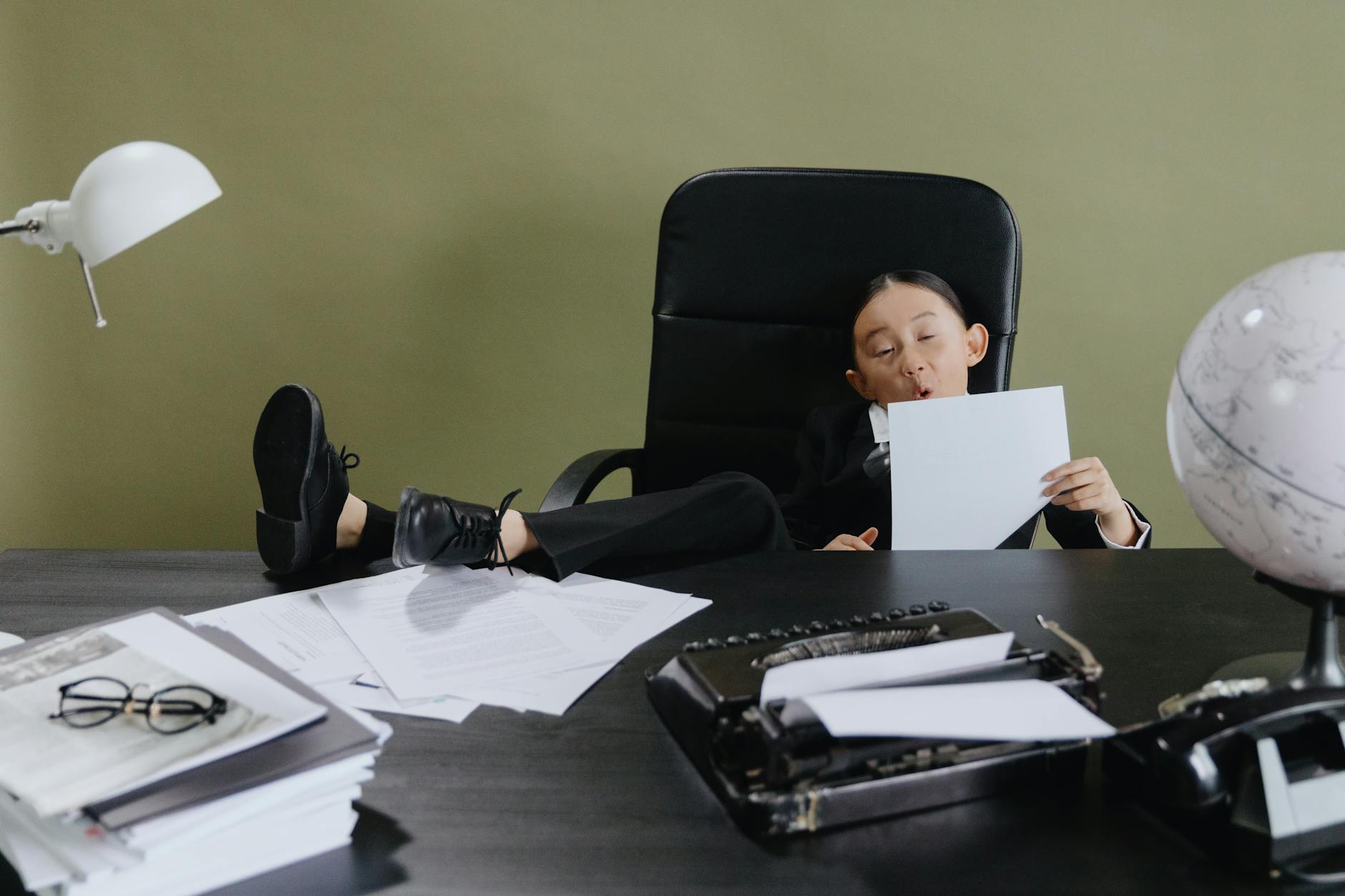 girl sitting on office chair holding white paper